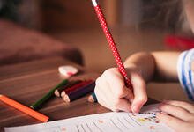 Kind füllt mit Bleistift einen Bogen aus.