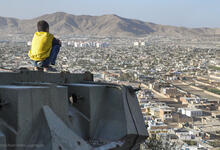 Afghanistan: Junge sitzt auf Panzer und schaut auf Kabul