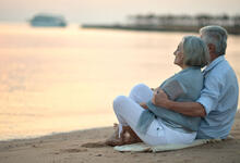 Rente: Senioren Paar sitzt am Strand, Sonnenuntergang