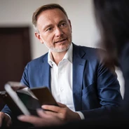 Christian Lindner am Schreibtisch im Gespräch mit einer Frau. 