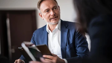 Christian Lindner am Schreibtisch im Gespräch mit einer Frau. 